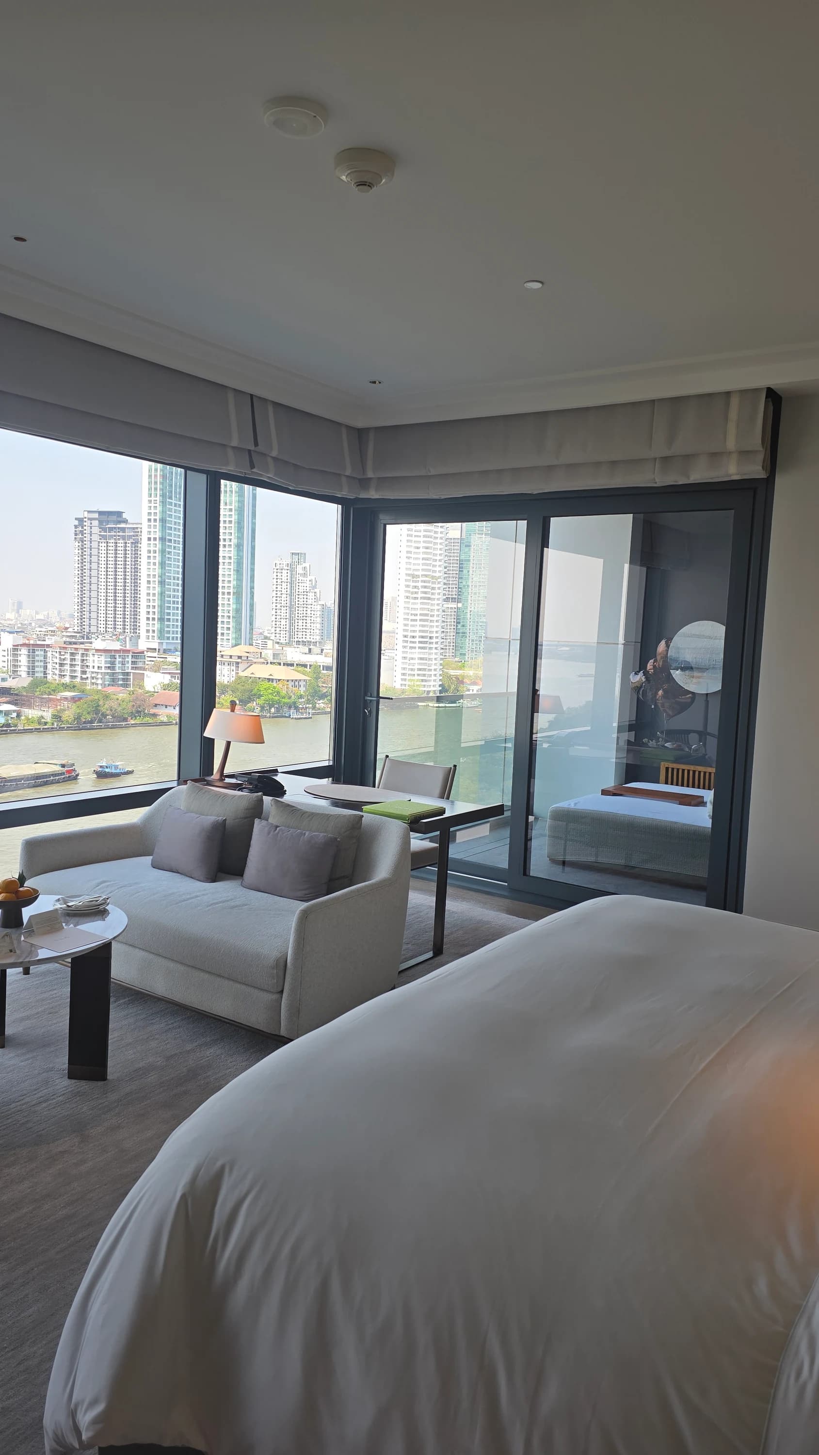 Capella Bangkok guest room bed with river-facing windows