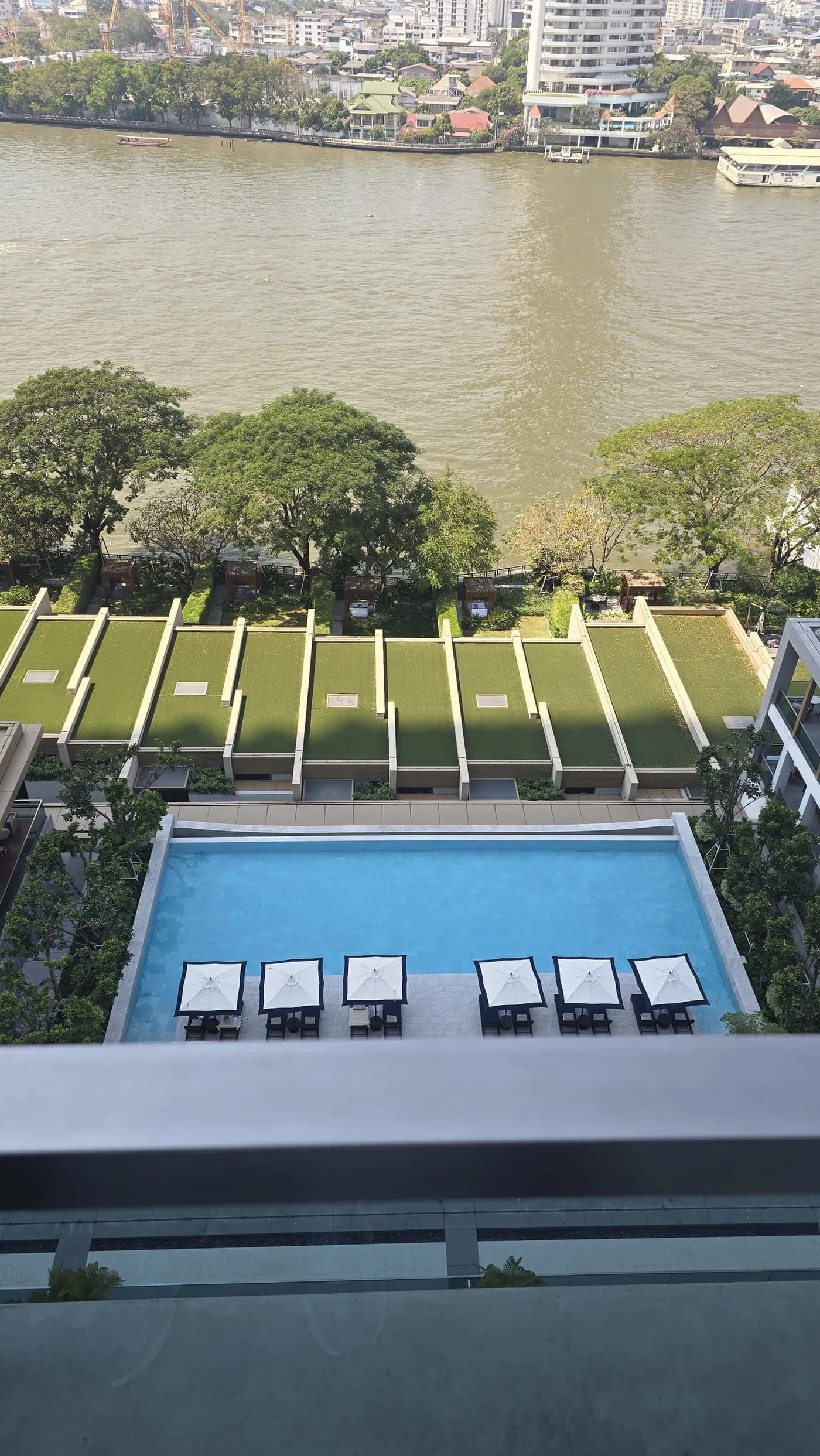 Balcony view toward pool and riverfront landscaping at Capella Bangkok