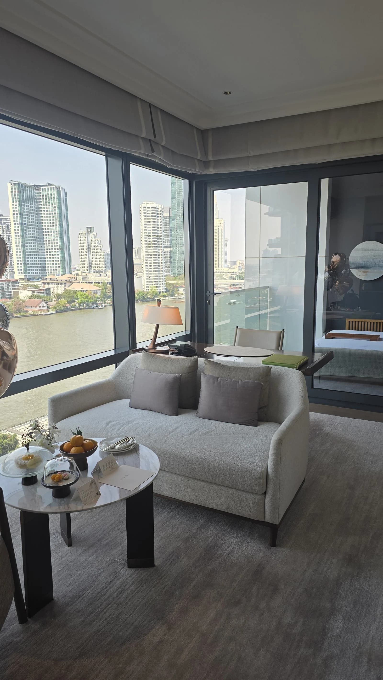 River-facing seating corner inside the Riverfront Premier Room at Capella Bangkok