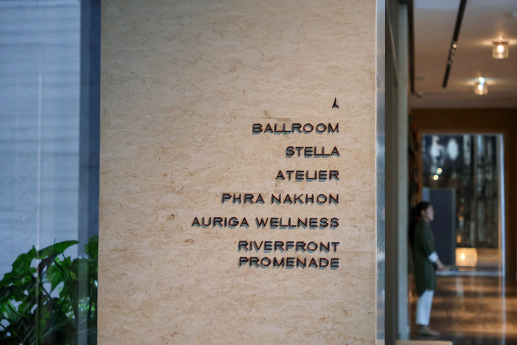 لوحة إرشادية ضمن جدار الردهة، تضم Ballroom وStella وAtelier وPhra Nakhon وAuriga Wellness وRiverfront Promenade، لتوجيه الضيوف إلى البارات والمطاعم ومرافق العافية.
