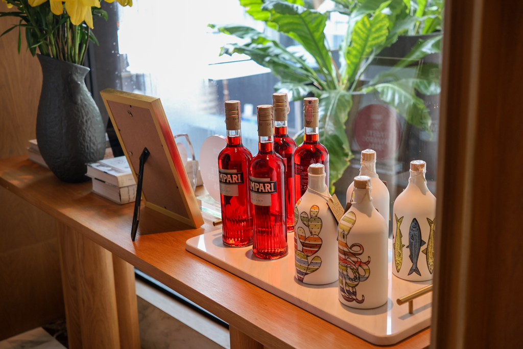Campari الأحمر بجوار زيت الزيتون البكر الممتاز Frantoio Muraglia عند نافذة متجر في فورسيزونز.
