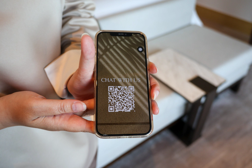تعليمات رمز QR بعنوان Chat with us، عرضها الموظف على هاتف.