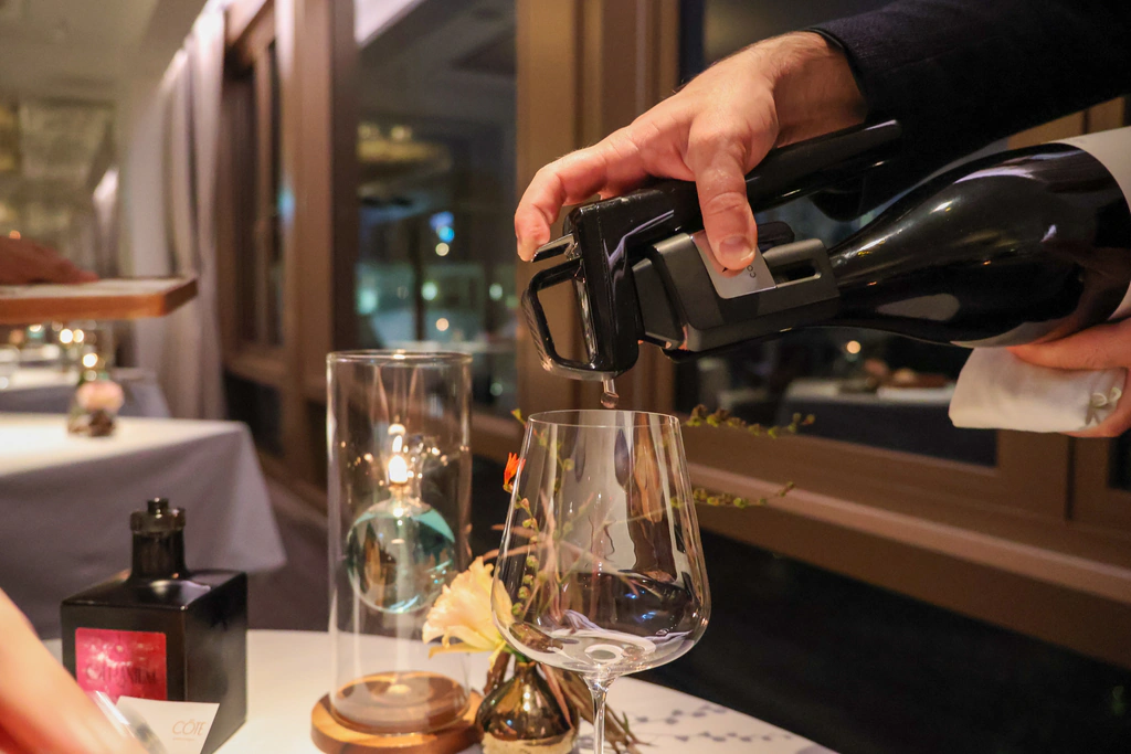سُكب النبيذ الأحمر بجهاز Coravin مثبت عند عنق الزجاجة.