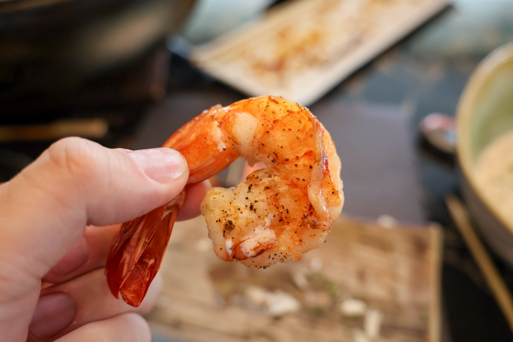 กุ้งย่างที่จับยกด้วยหางให้เห็นผิวแดง