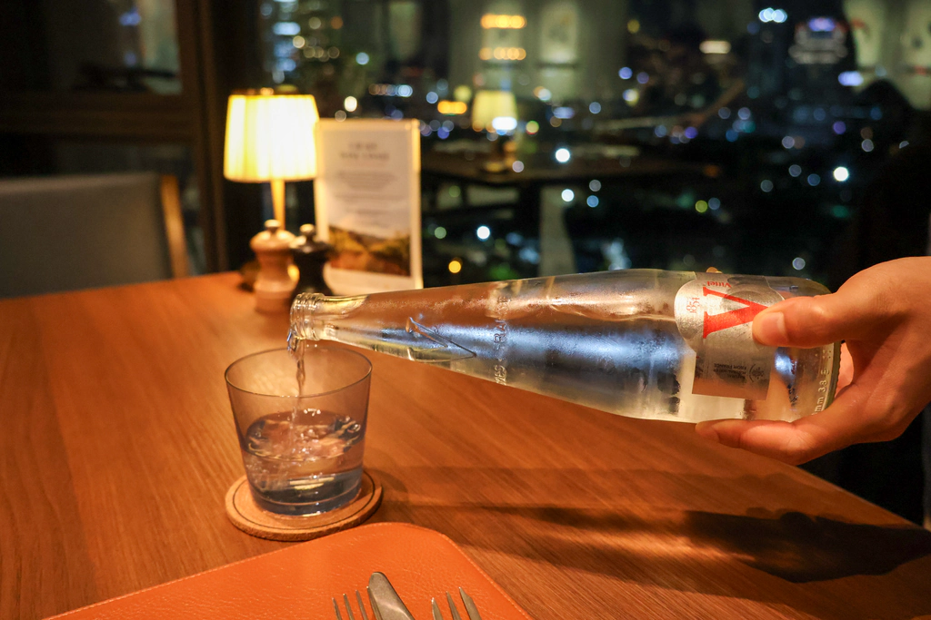 รินน้ำ Vittel ลงแก้วบนที่รองกลม