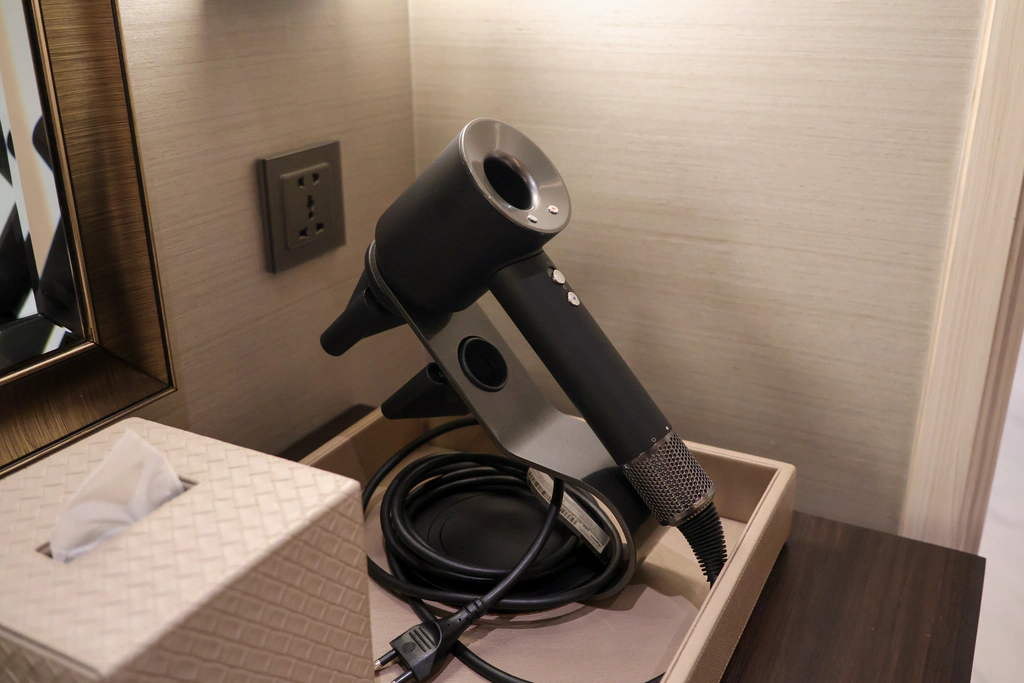 ไดร์ Dyson พร้อมสายและหัวเป่าบนแท่นกับถาด