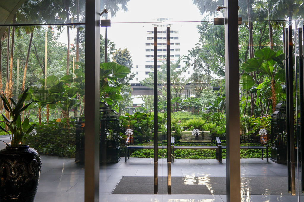 สวนและม้านั่งที่มองผ่านประตูกระจกจากล็อบบี้