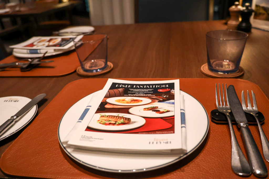 แผ่น Dîner Fantastique บนจานข้างอุปกรณ์ ผ้าและแก้ว