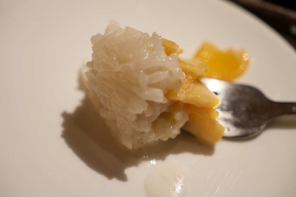 ข้าวเหนียวใต้ชิ้นมะม่วงที่ตักขึ้นมา