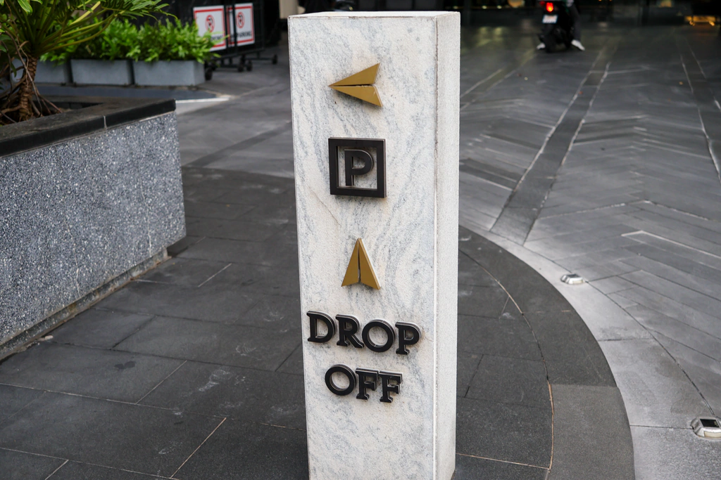 ตัว P คำว่า Drop Off และลูกศรบนเสาเล็กริมทางรถ