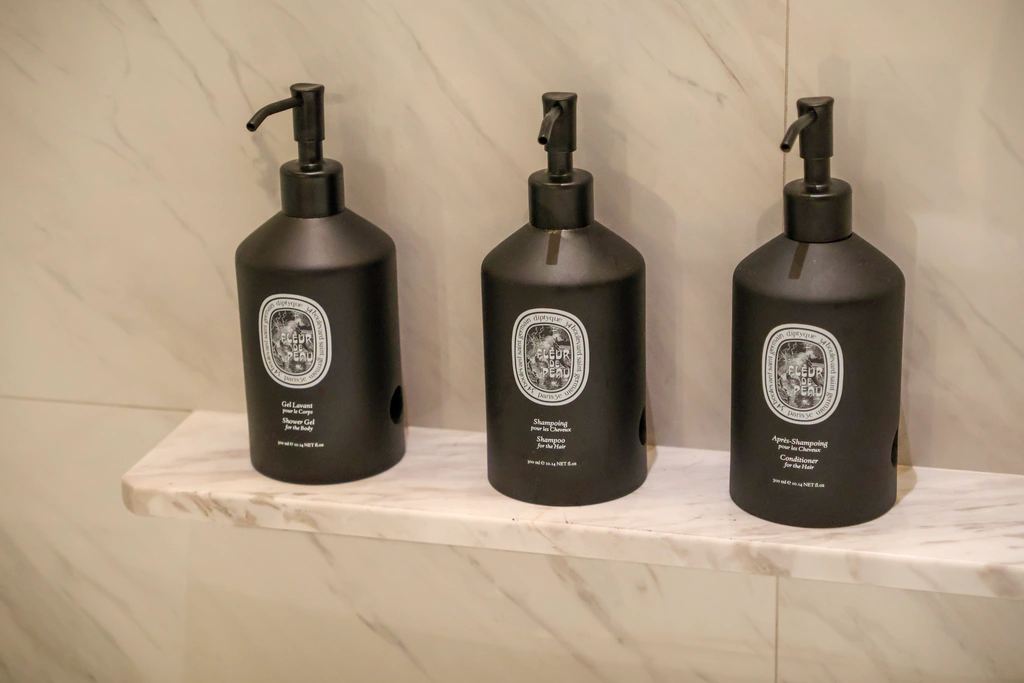 Diptyque Fleur de Peau สามขวดบนชั้นข้างอ่าง