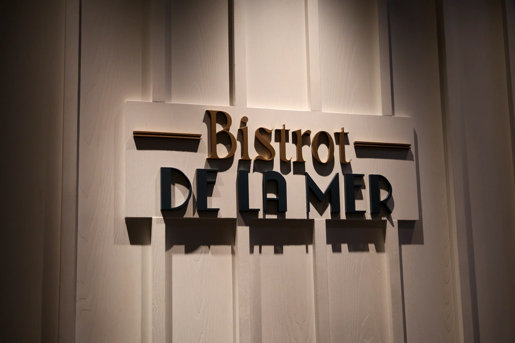 ชื่อ Bistrot De La Mer ตัวนูนบนผนังแผงขาว