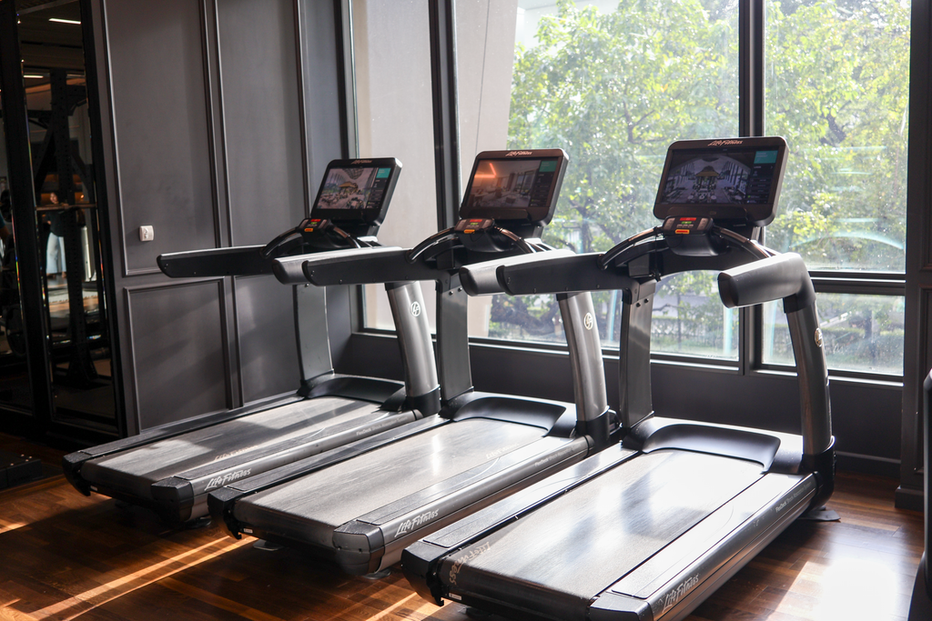 ลู่วิ่ง Life Fitness สามเครื่องหันสู่ต้นไม้นอกหน้าต่าง