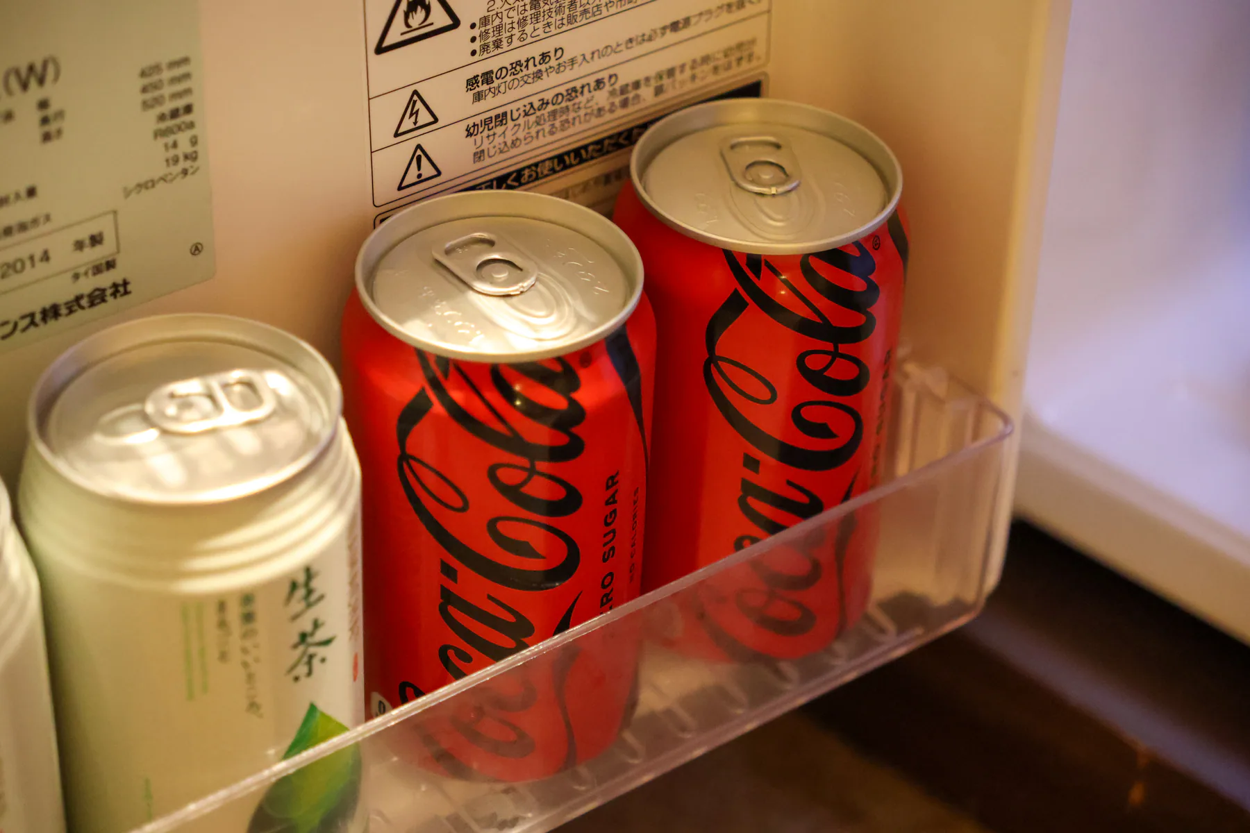 عبوتان من الشاي الأخضر وعبوتان من Coca-Cola Zero في باب الثلاجة
