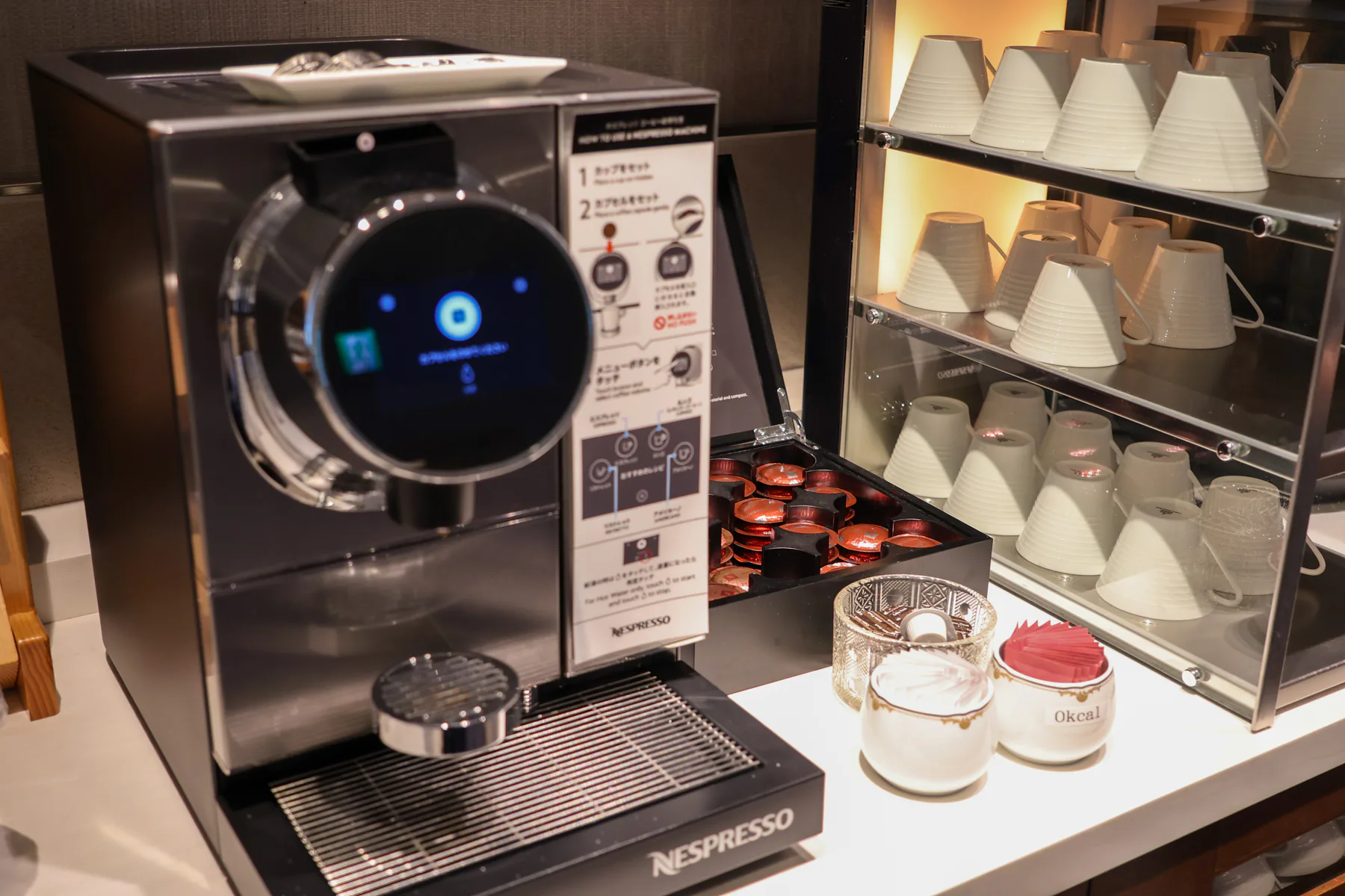 ماكينة Nespresso وكبسولات وأكواب بيضاء مرتبة في الصالة