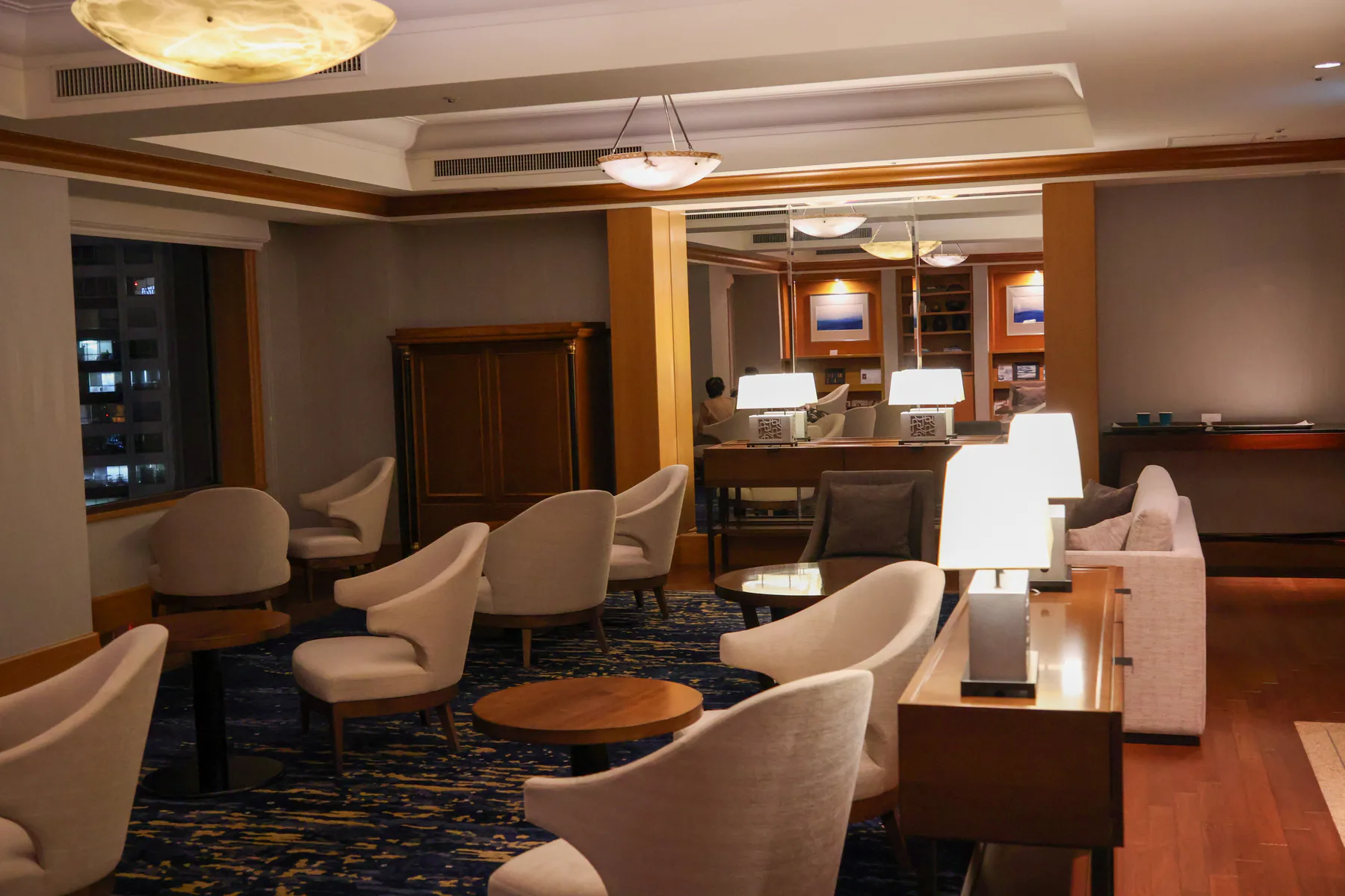 أرائك بيضاء ومصابيح أرضية وطاولات نافذة في View Lounge بالطابق 27