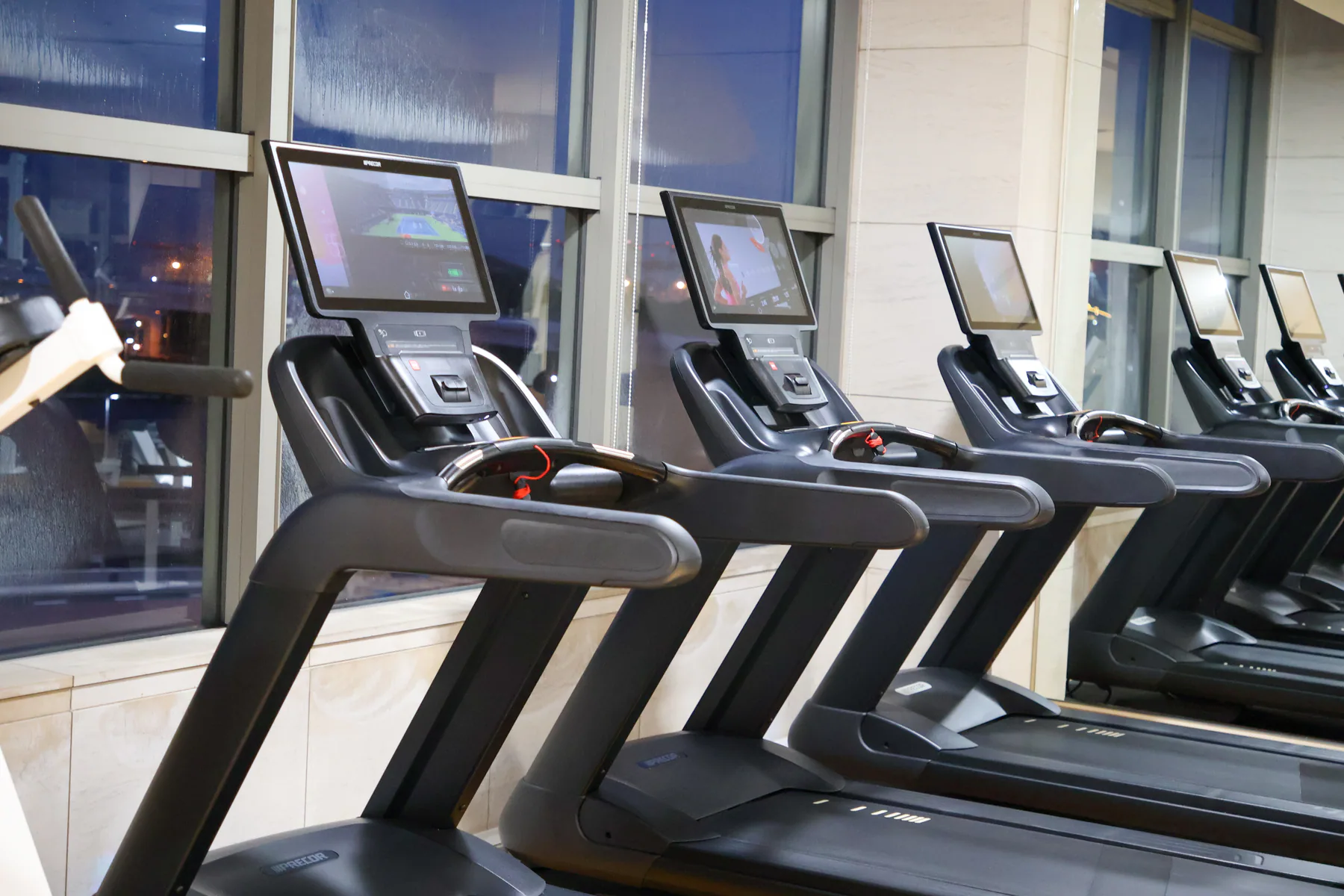صف مشايات Precor بجوار نوافذ صالة Le CLUB الرياضية