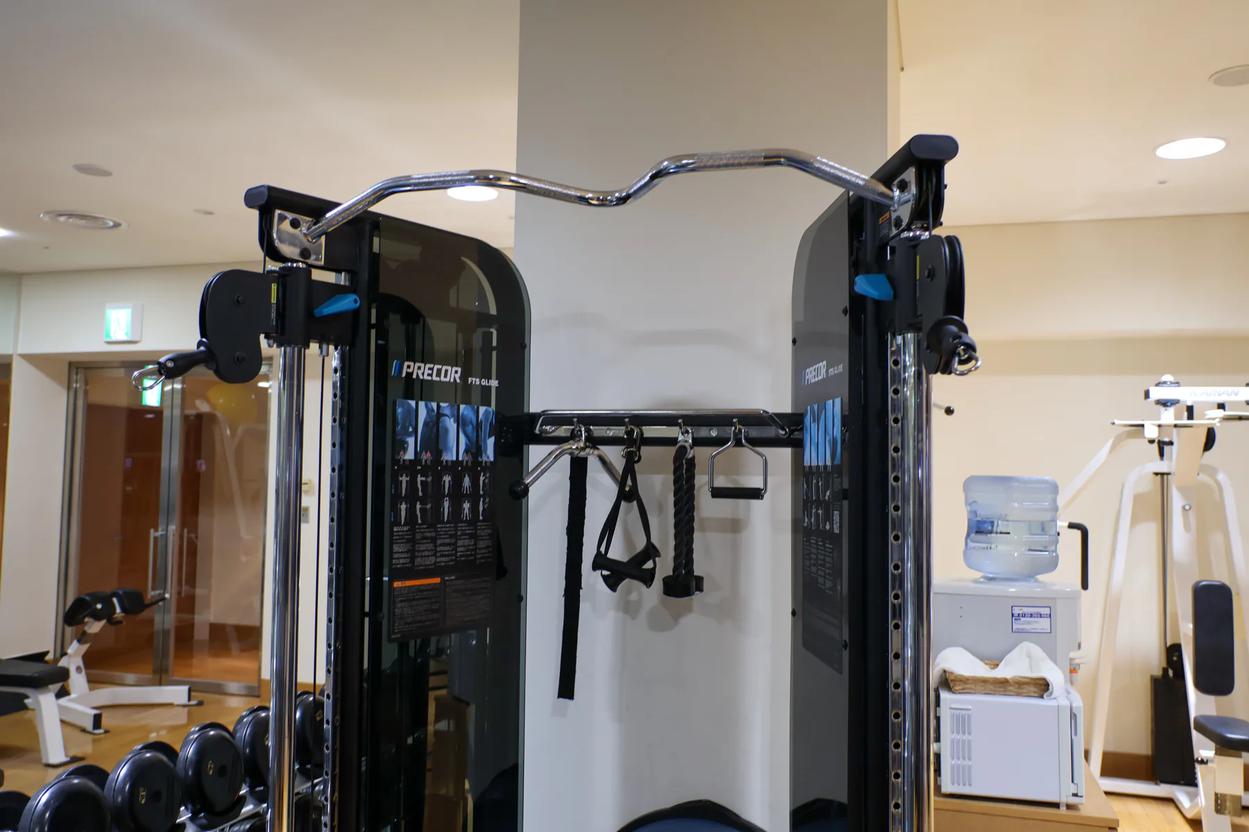 جهاز كابلات Precor FTS Glide وملحقات وأوزان يدوية وماء بالقرب منه